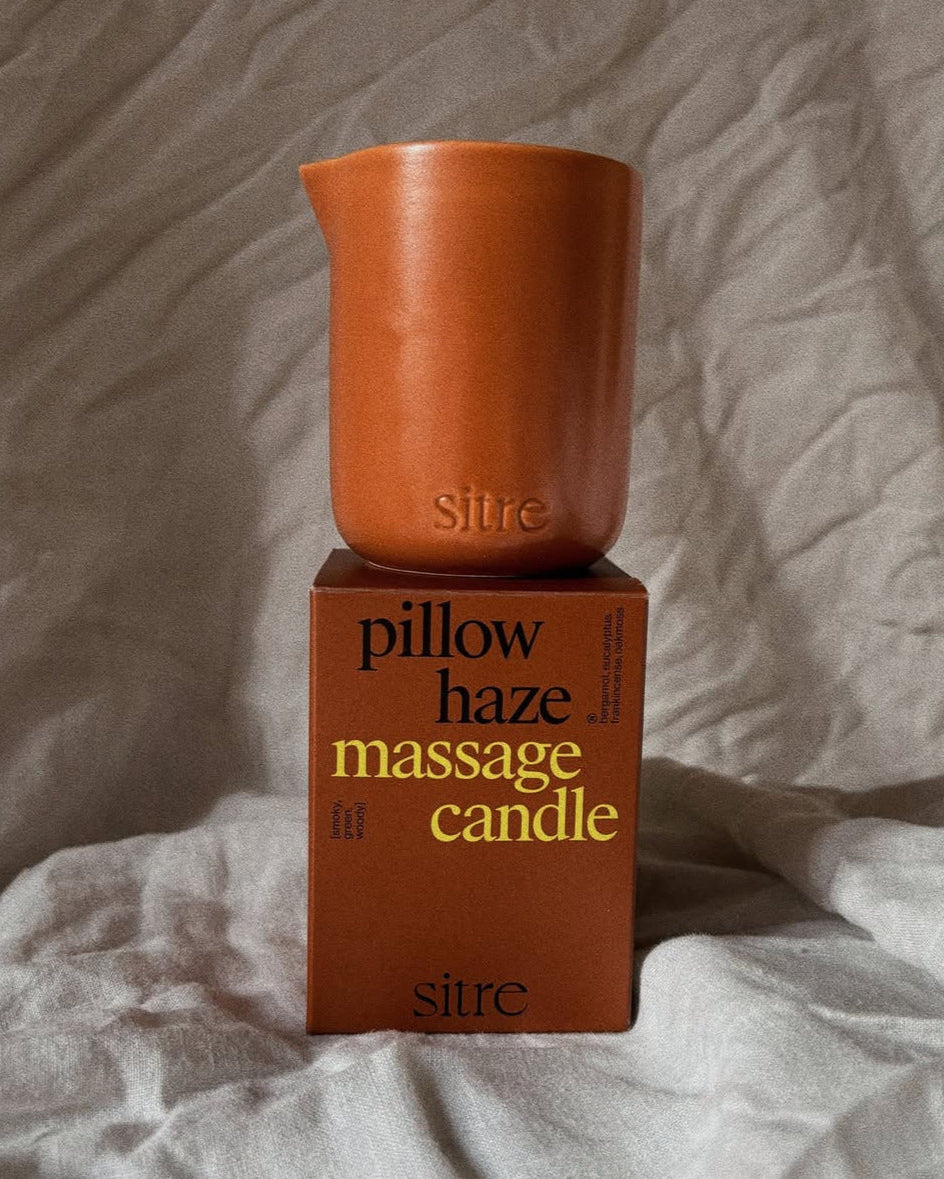 Sitre pillow haze massage candle on its packaging against a textured fabric background